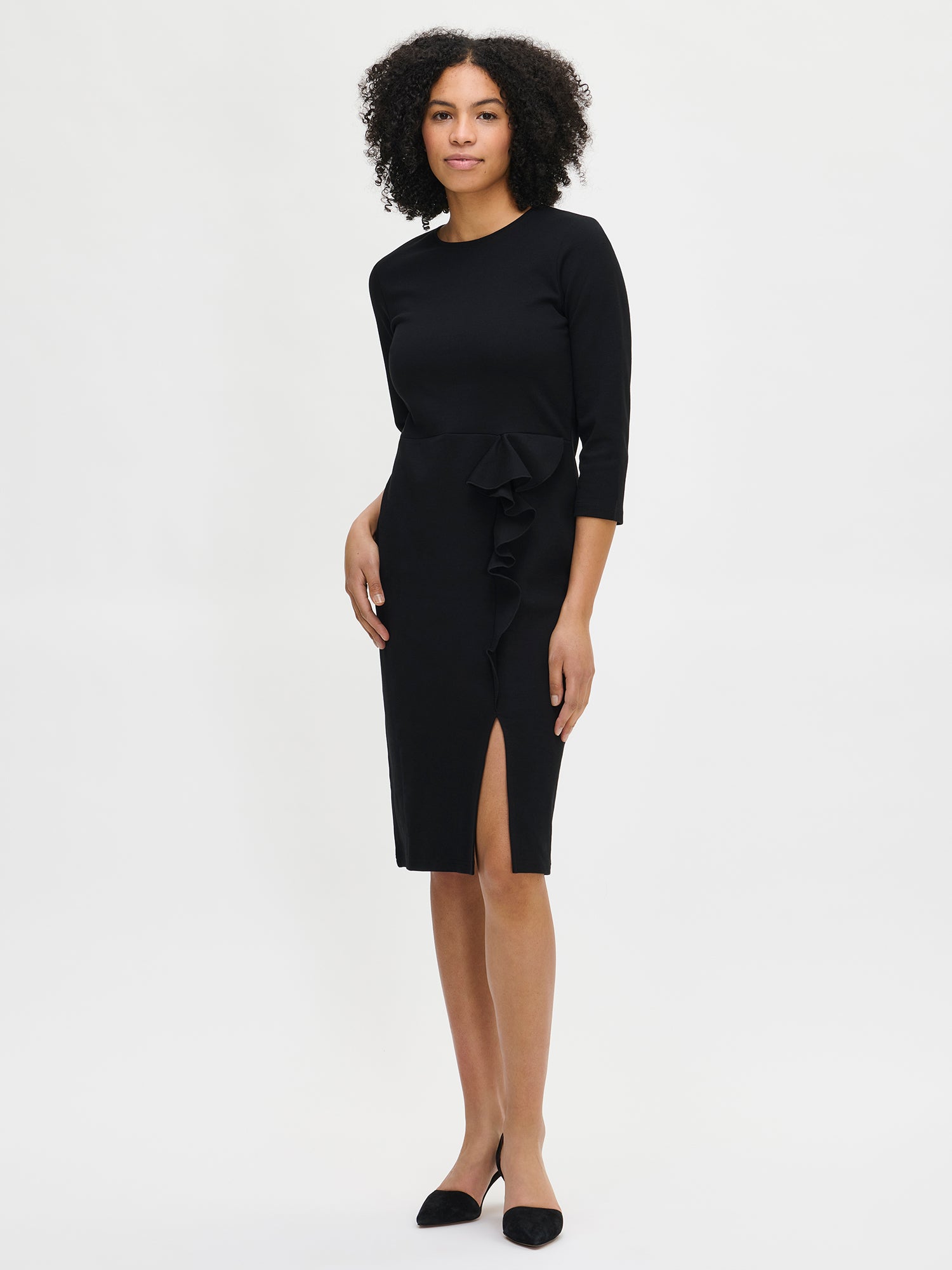 Nanso women’s black Opera dress, knee-length fitted style with round neckline, three-quarter sleeves, and frill detail with slit, worn by model in full-body photo.