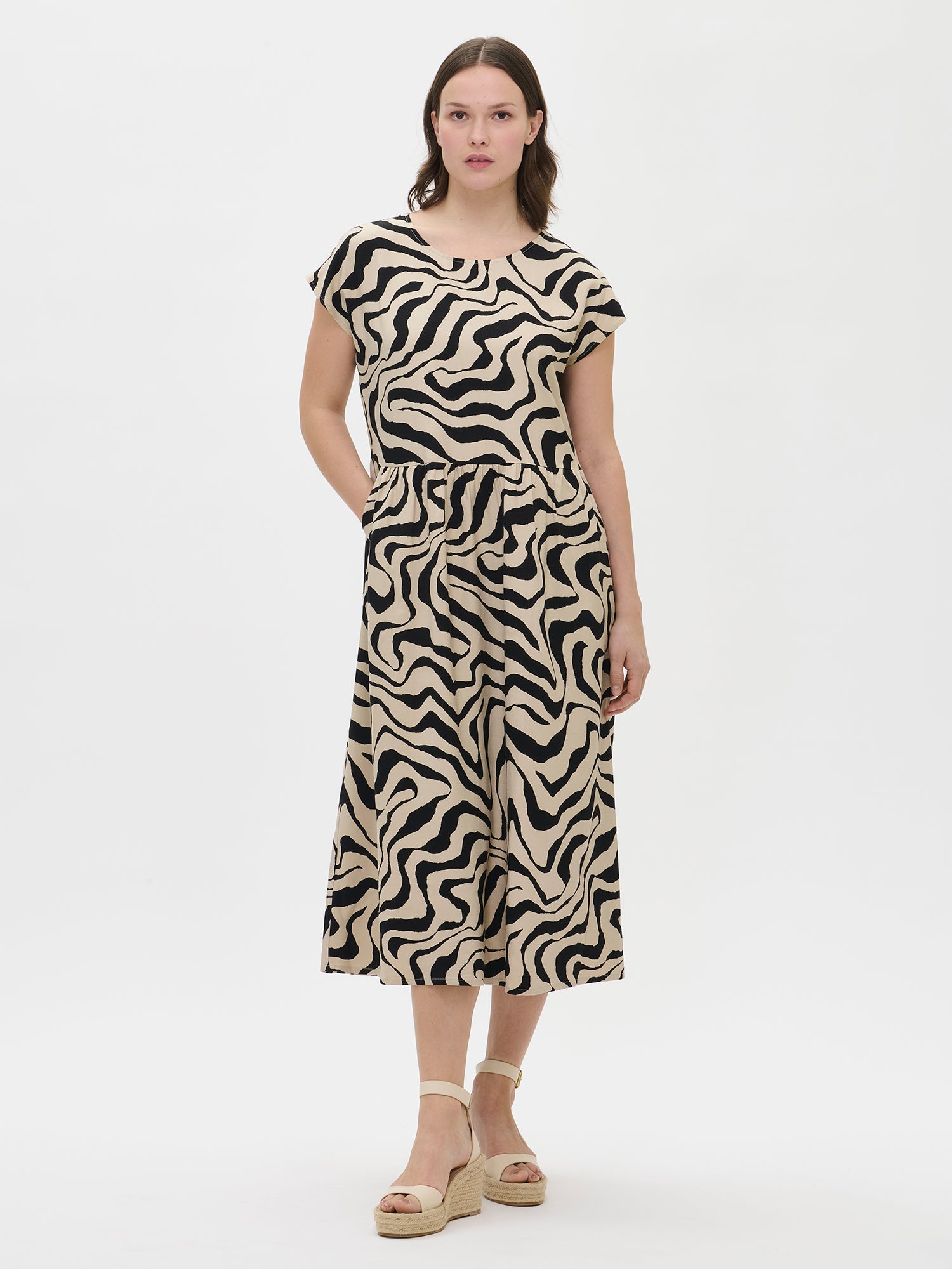 Nanso women’s patterned beige Savanna dress on the model, front view. Relaxed fit with a calf-length hem.