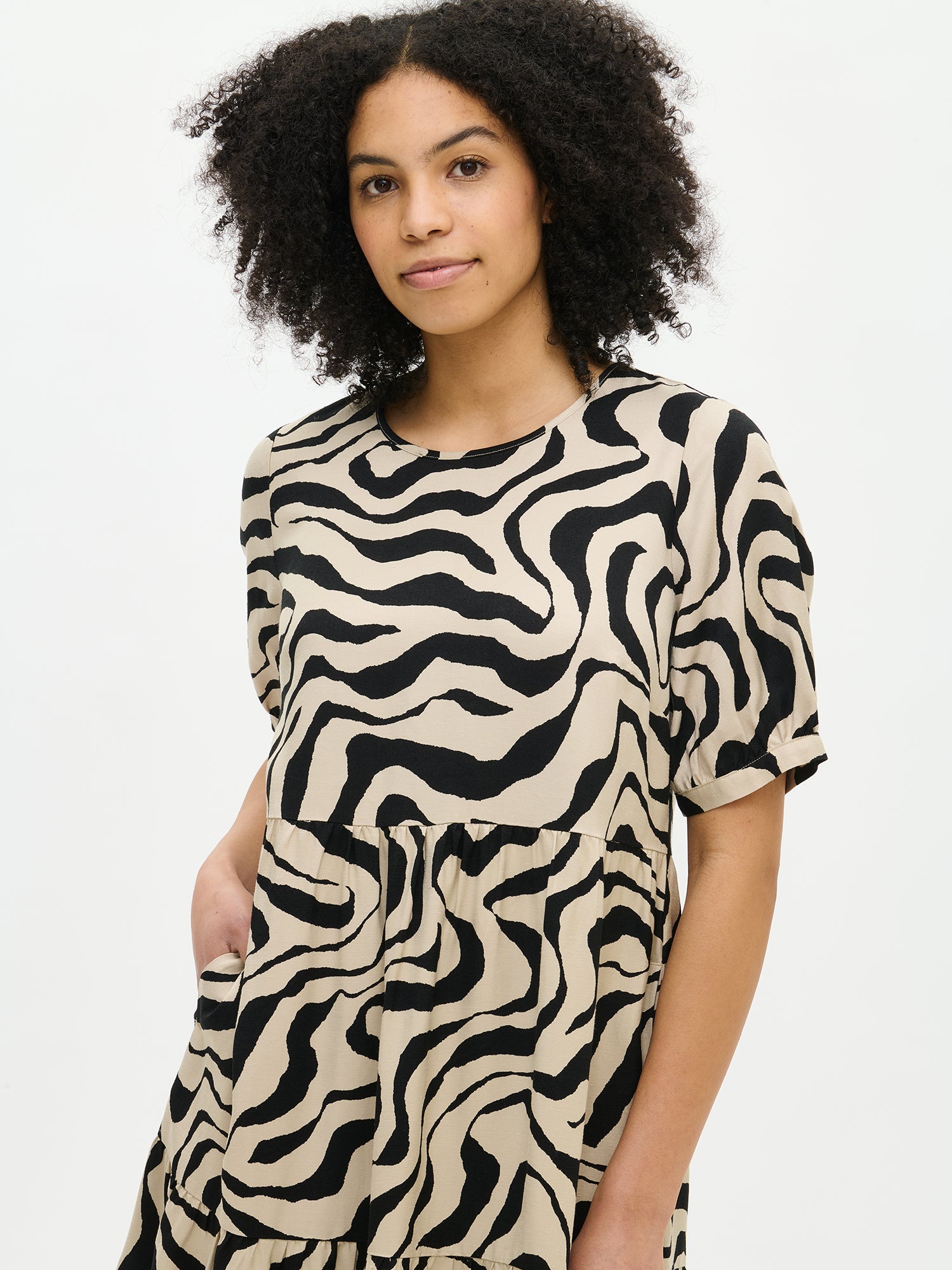Nanso women's beautiful patterned beige Savanna midi dress with voluminous frill layers and short puff sleeves, close-up.