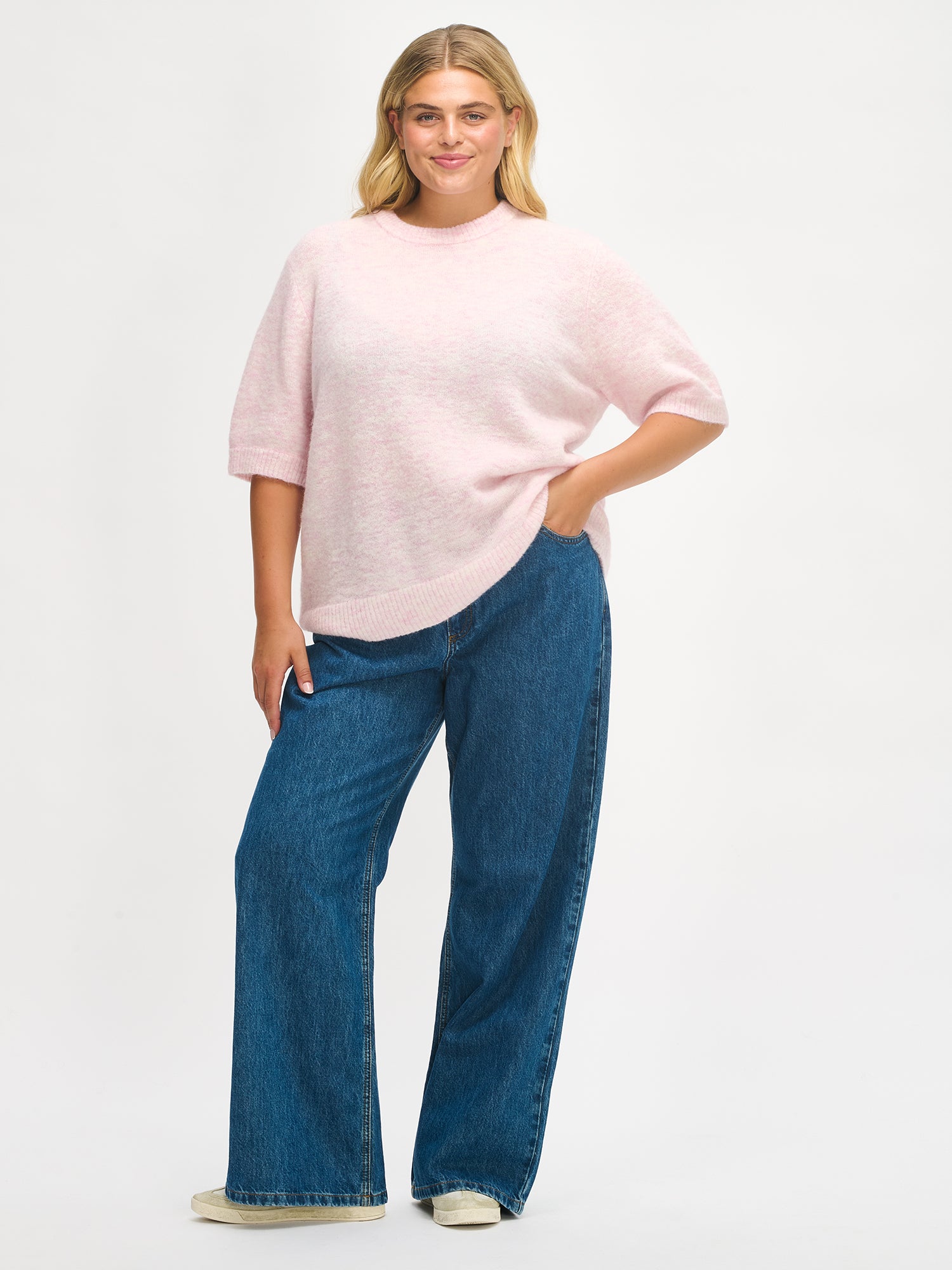 Nanso Women’s Tuohi knit sweater in pink, hip-length style with round neckline and short half sleeves, worn by plus model, size XL, in full-body photo.