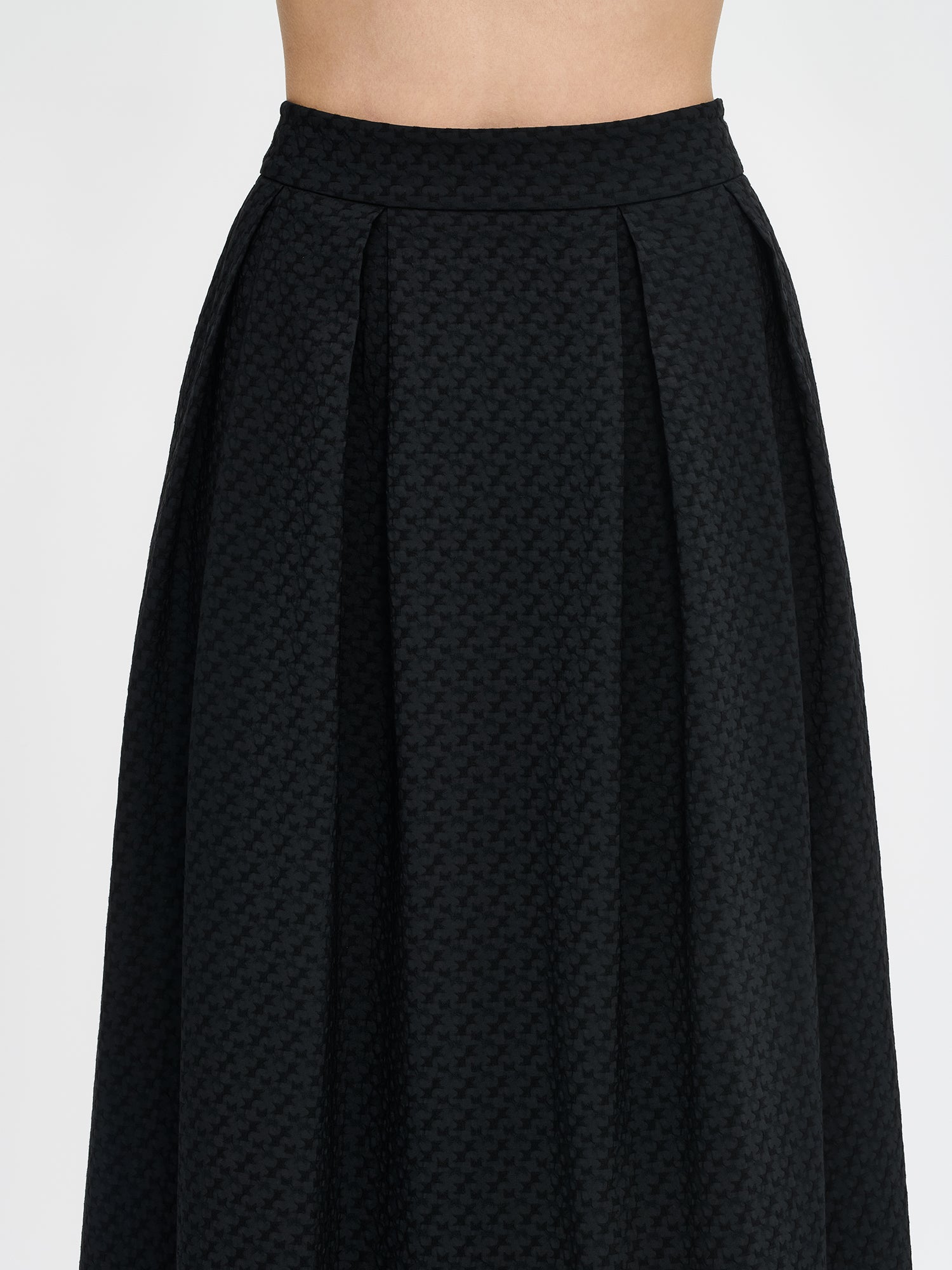 Nanso women’s black Reliefi skirt, close-up of waist showing pleats and textured fabric, worn by model.