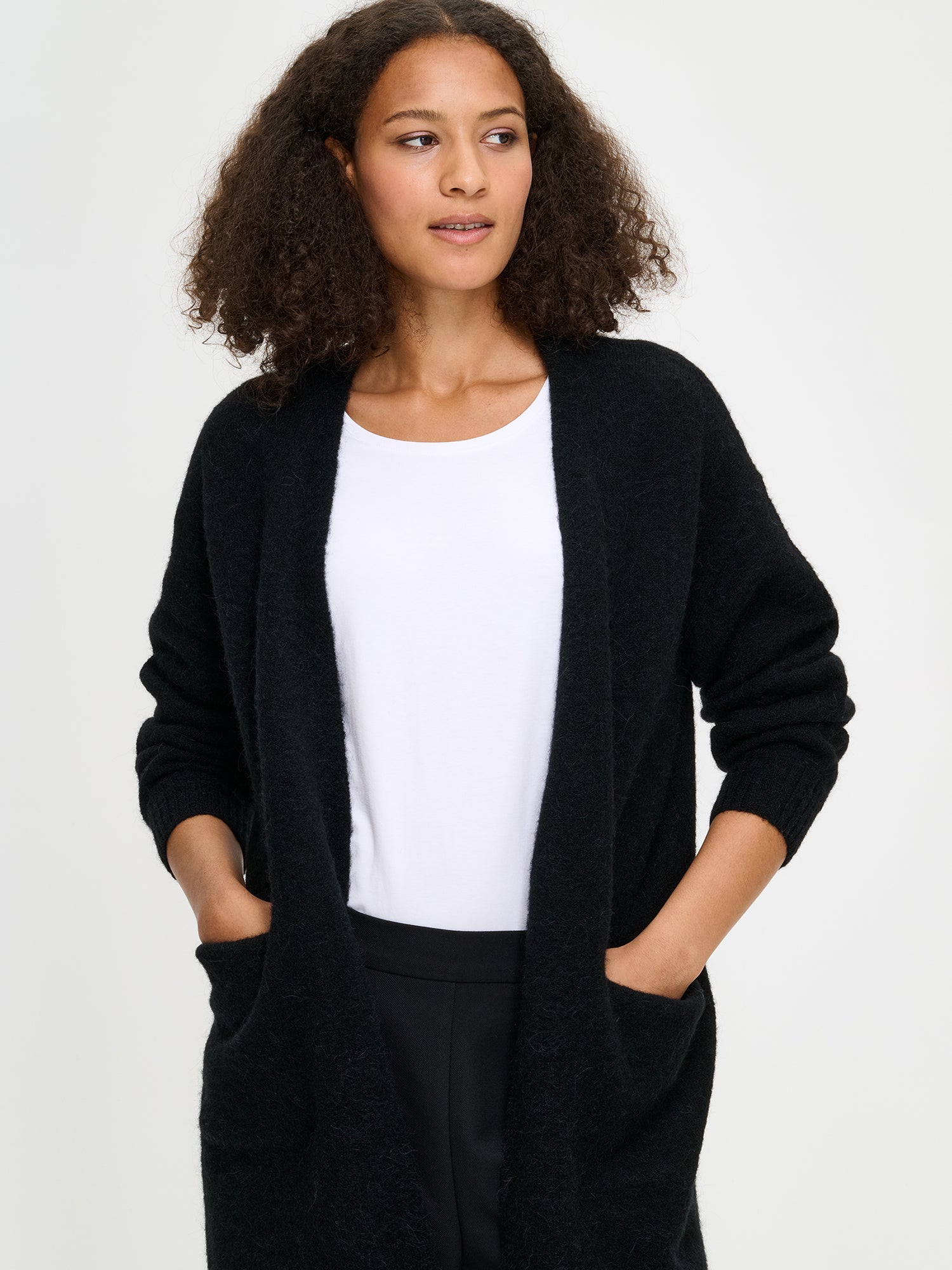 Nanso women’s black Tuohi knit cardigan, soft knit with relaxed fit, ribbed cuffs and hem, worn by model in close-up photo.