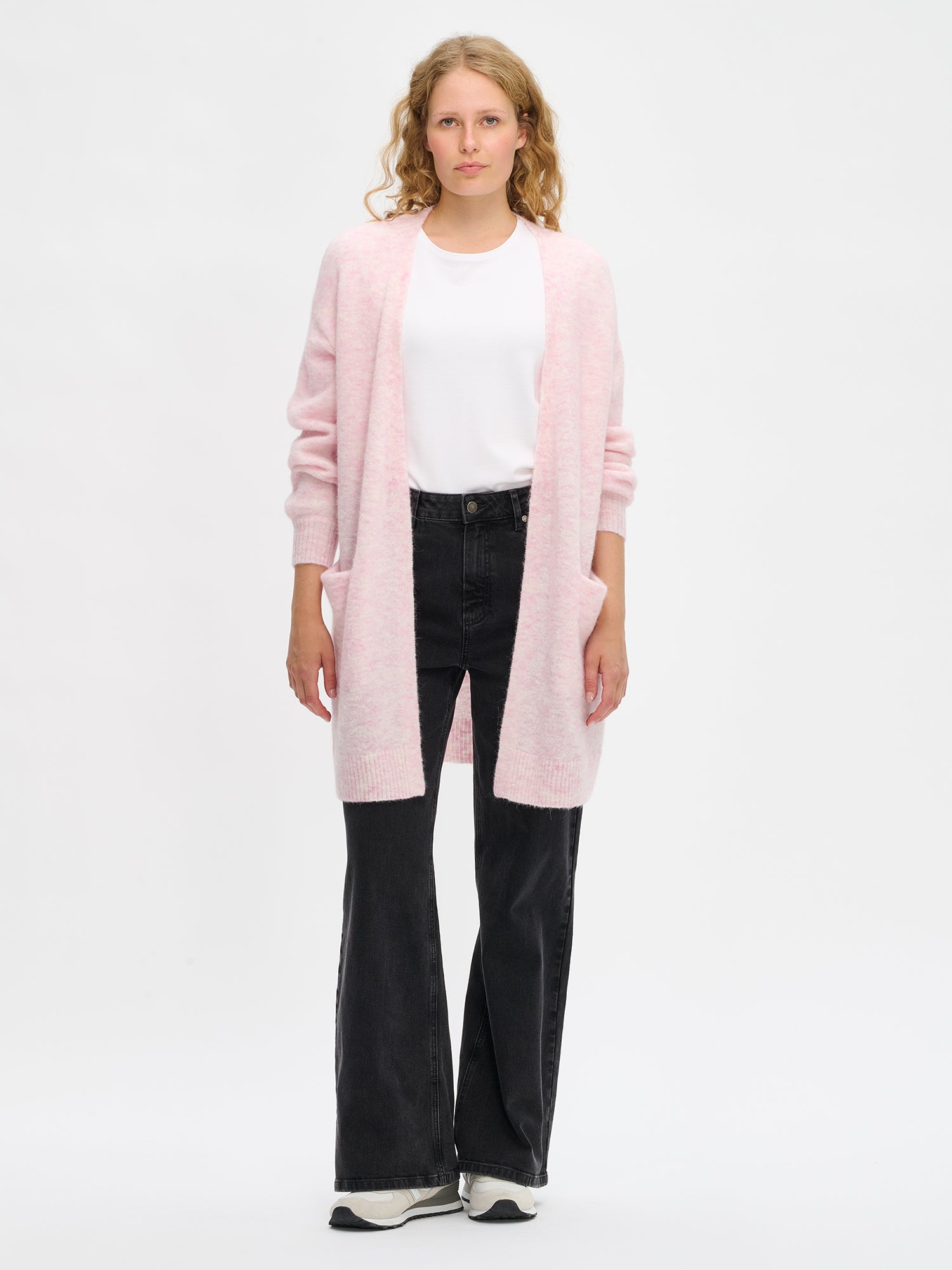 Nanso women’s pink Tuohi knit cardigan, thigh-length style with long sleeves and front pockets, worn by model in full-body photo.