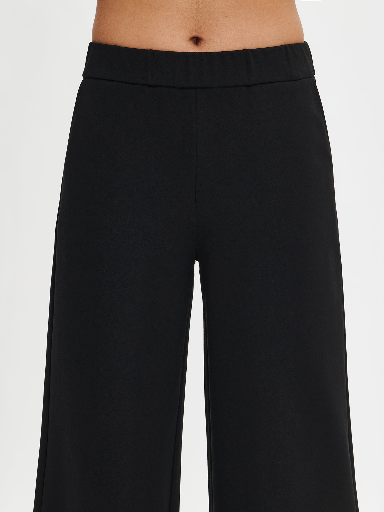 Women's Alma trousers in black color for a relaxed fit. The trousers feature side pockets and an elastic waistband. Worn by a model in size S. 