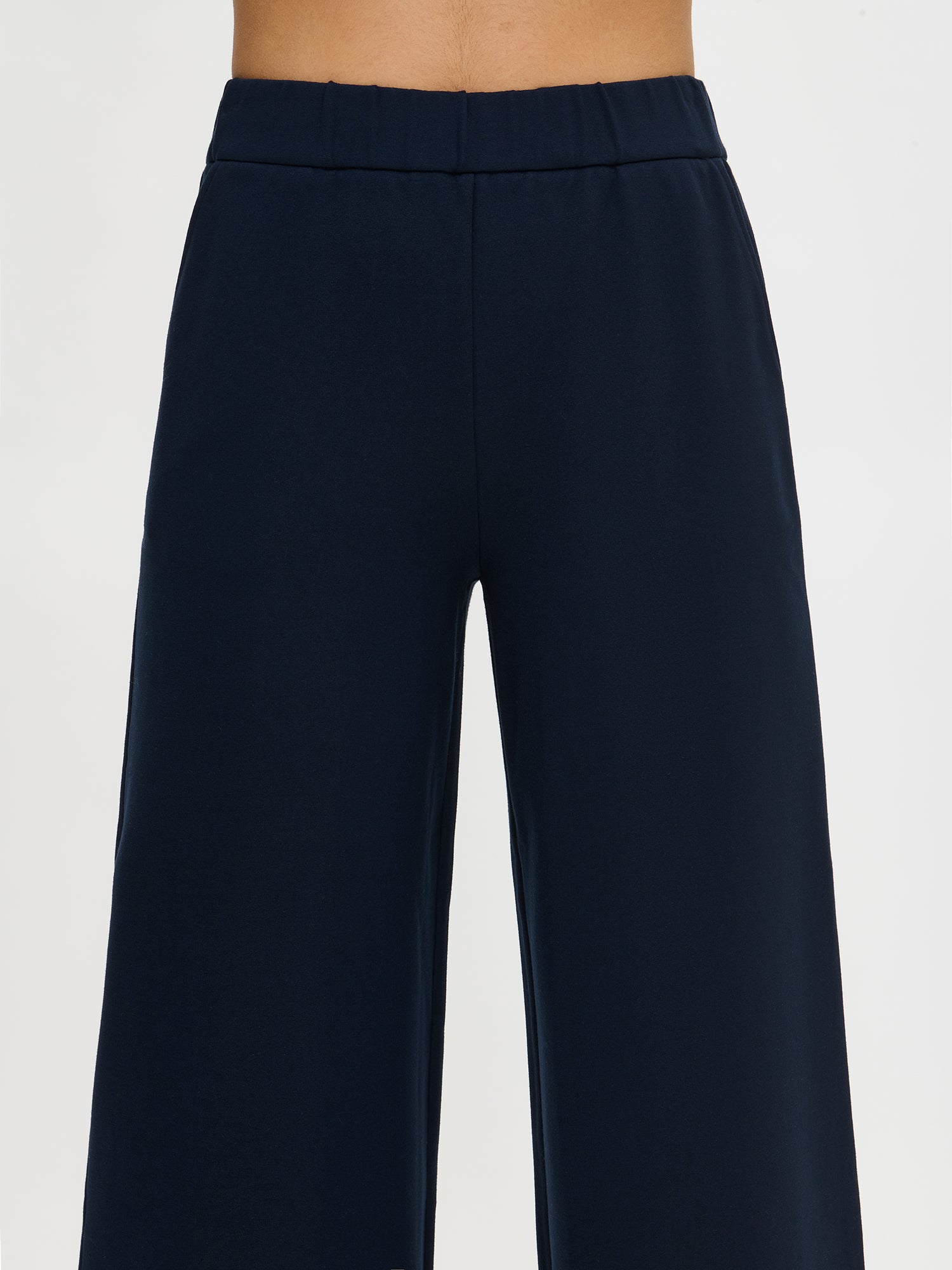 Women's Alma trousers in a dark blue color for a relaxed fit. The trousers feature side pockets and an elastic waistband. Worn by a model in size S.