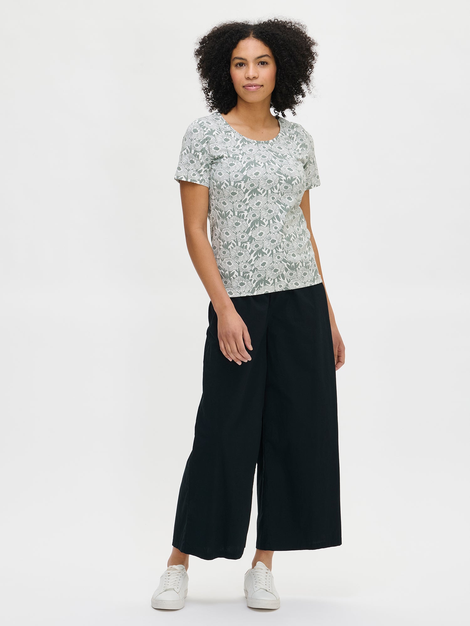 Women's patterned Samettikukat t-shirt in green. The fitted t-shirt has a wide round neckline and short sleeves. Worn by a model in size S.