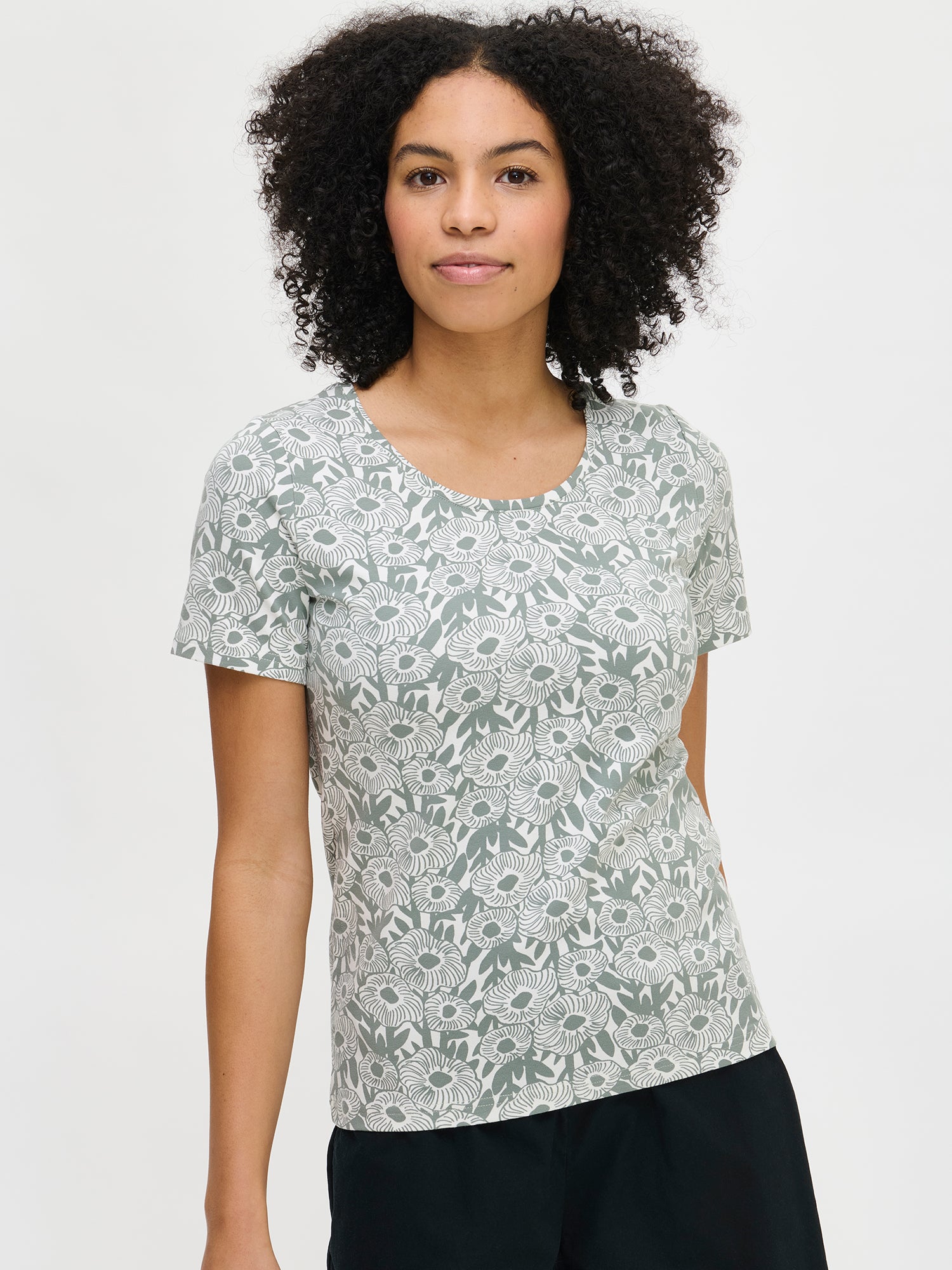 Women's patterned Samettikukat t-shirt in green. The fitted t-shirt has a wide round neckline and short sleeves. Worn by a model in size S.