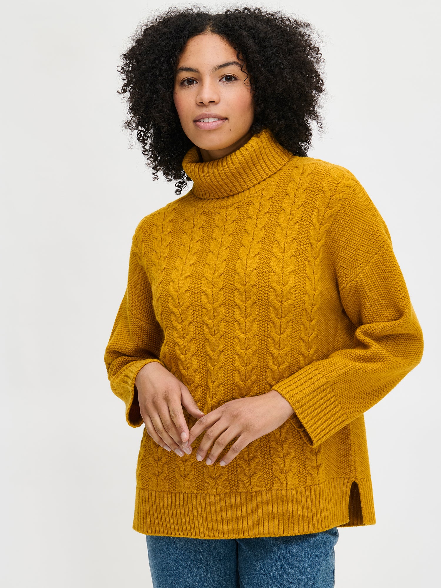 Woman wearing a yellow cable knit sweater on a white background