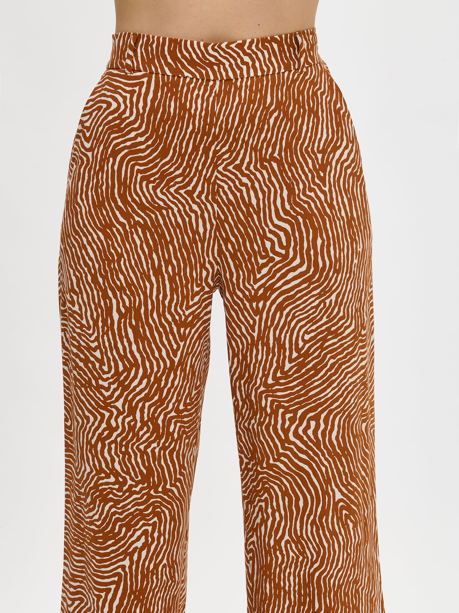 The brown JÄLKI culottes trousers for women feature a playful pattern. Pair the cropped trousers with a matching JÄLKI shirt for a complete look. Worn by a model in size 36.