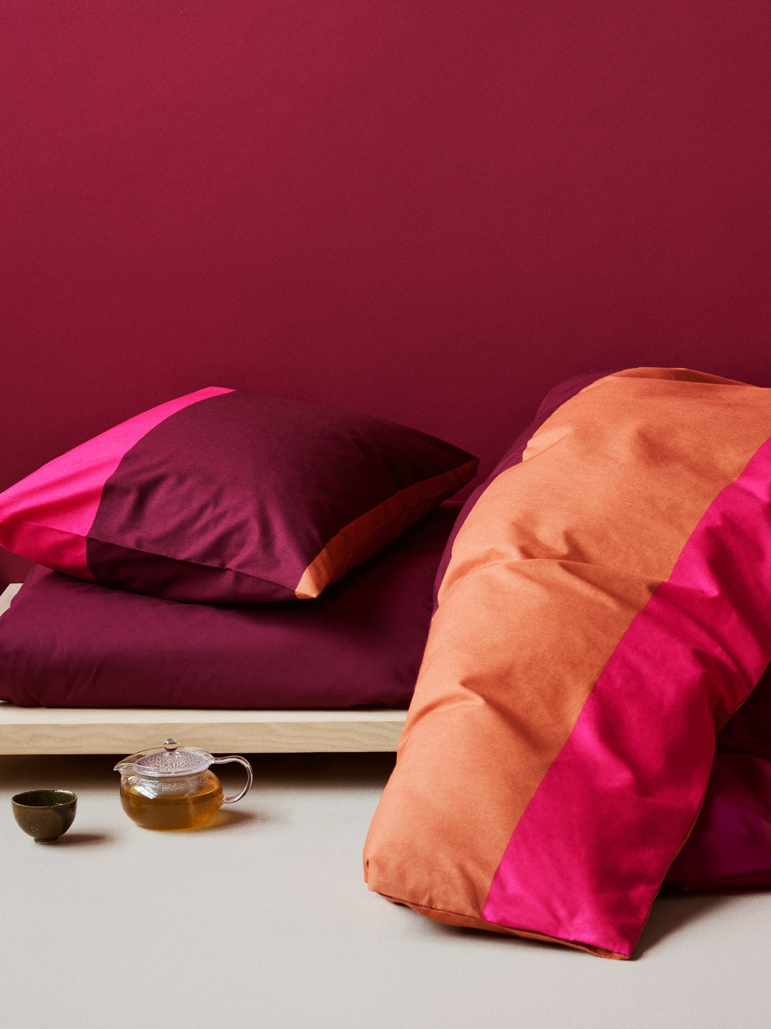 Nanso's red Trio duvet cover set features a beautiful wide striped pattern, on a bed