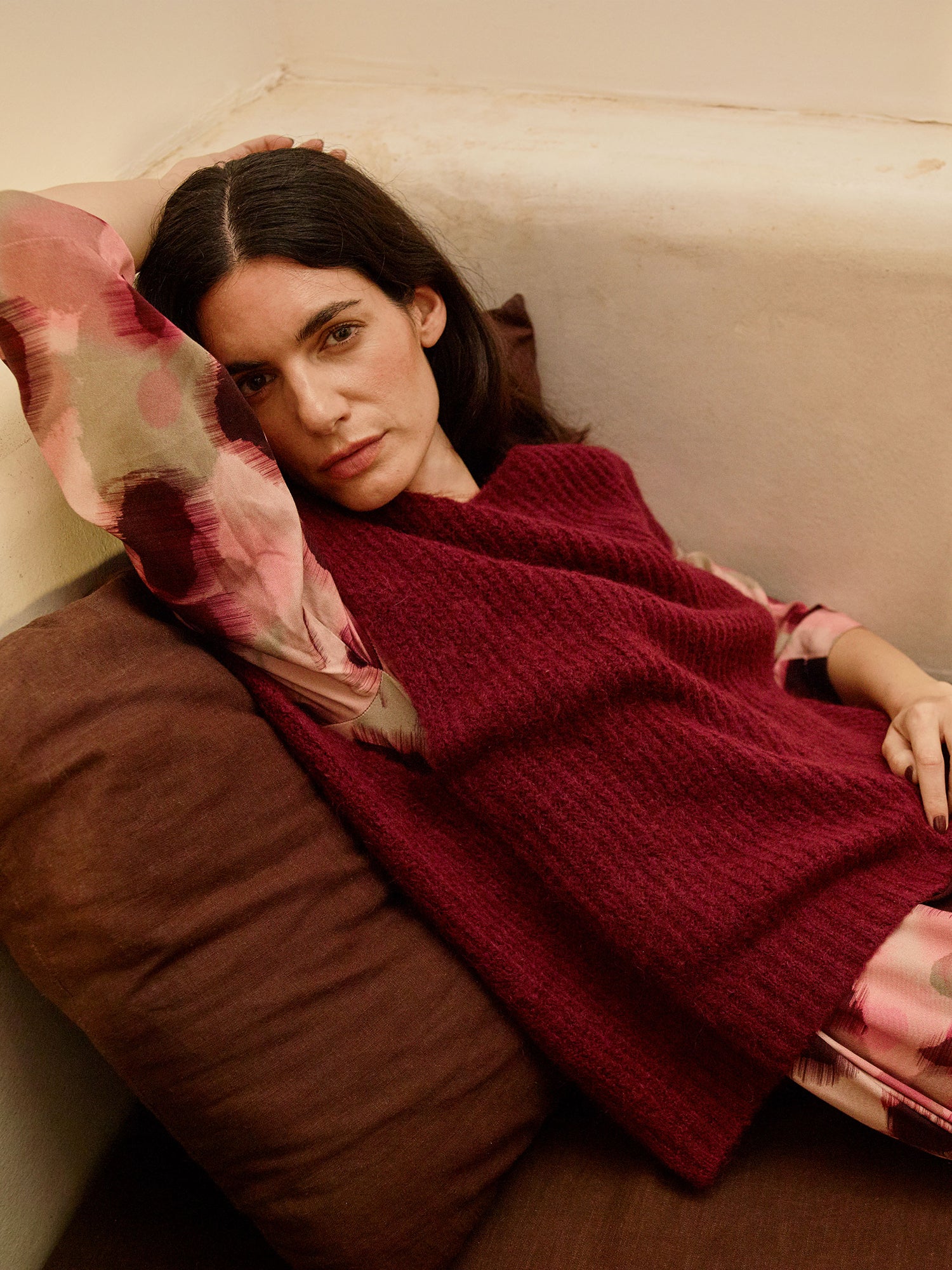 Nanso women's luxuriously soft and wonderfully chunky, the Karamelli knitted vest in a rich wine-red hue on a model with a patterned dress