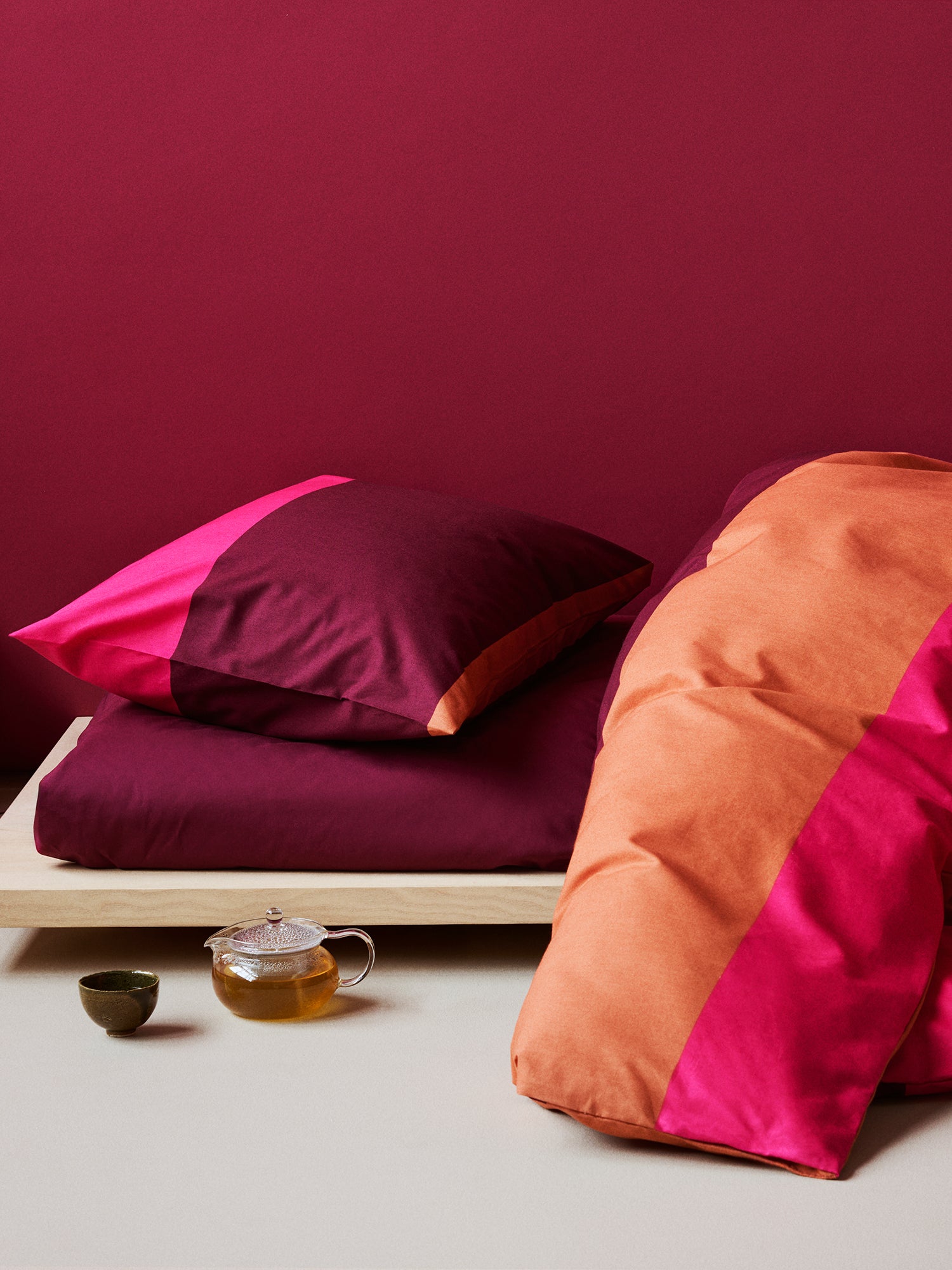 Nanso's red Trio duvet cover set features a beautiful wide striped pattern, on a bed