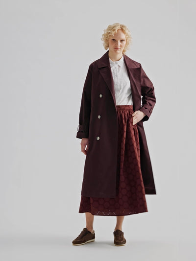 A timeless Brown trench coat on a blonde model, the coat open.